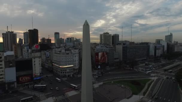 Aerial Drone scen av obelisken i Buenos Aires, Argentina, vid soluppgången på morgonen. 9 de Julio main Avenue, 9 juli. Trafik och människor går för att arbeta. Kamera antenn reser flytta bakåt genom Diagonal Norte Street. — Stockvideo