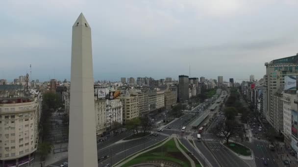 Εναέριος κηφήνας σκηνή του Οβελίσκου, Μπουένος Άιρες, Αργεντινή, το πρωί. 9 de Julio main Avenue, 9 Ιουλίου. Κίνηση και οι άνθρωποι. Εναέρια ταξίδια να κινείται προς τα εμπρός προς τον Οβελίσκο και τη λεωφόρο. — Αρχείο Βίντεο