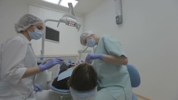 牙科医生和牙科助理工作真正牙科手术的患者牙齿上 — 图库视频影像