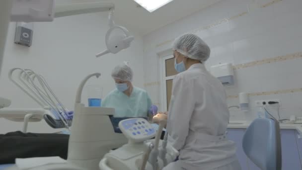 Zubaři a zubní asistent pracuje na pacienty zuby v reálné zubní chirurgii