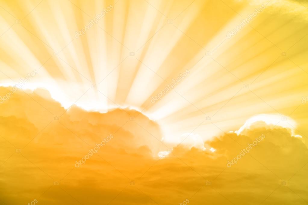 Gold sky and rays of light shining down with clouds Stock Photo by