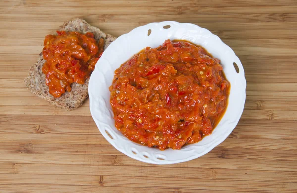 Servische ajvar in een glazen kom op een houten achtergrond — Stockfoto