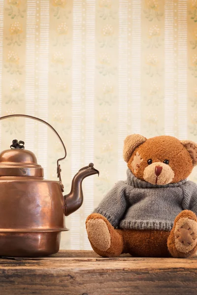 Teddy bear and copper kettle on background of old wallpaper — Stock Photo, Image