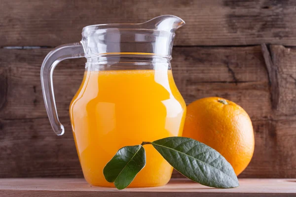 Glas jus d'orange houten tafel met groen blad, vers drankje — Stockfoto