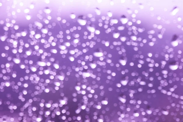 Přírody bokeh, fialové abstraktní dešťové kapky na okenní sklo. — Stock fotografie