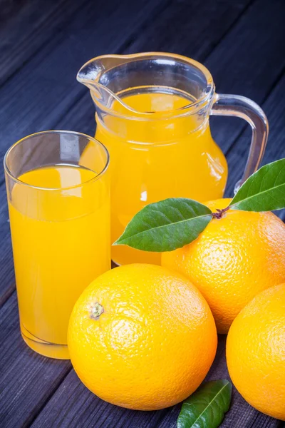 Oranges et jus sur la table rustique nature morte — Photo