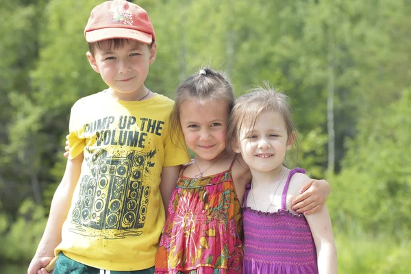 Tres niños felices sobre fondo verde del bosque — Foto de Stock