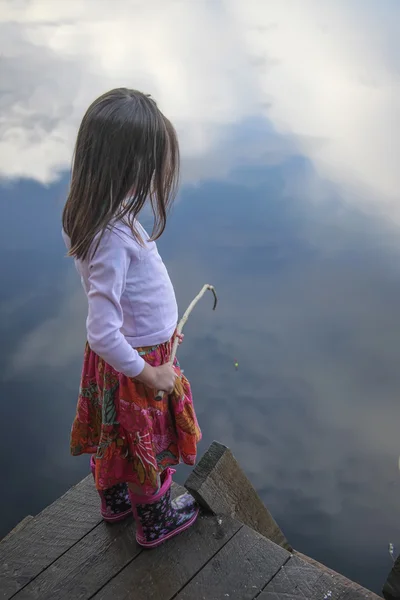 Retrato de una niña pescando en el lago reflejando el cielo — Foto de Stock