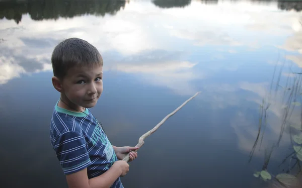 Retrato de un niño pescando en el lago reflejando el cielo — Foto de Stock