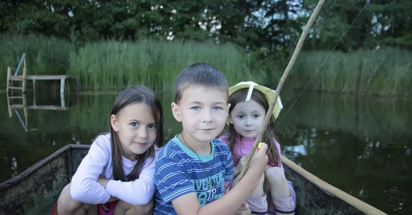 Retrato de tres niños pescando en un barco — Foto de Stock