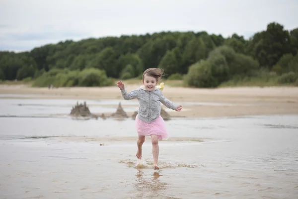 Kleines Mädchen läuft an einer sandigen Küste — Stockfoto