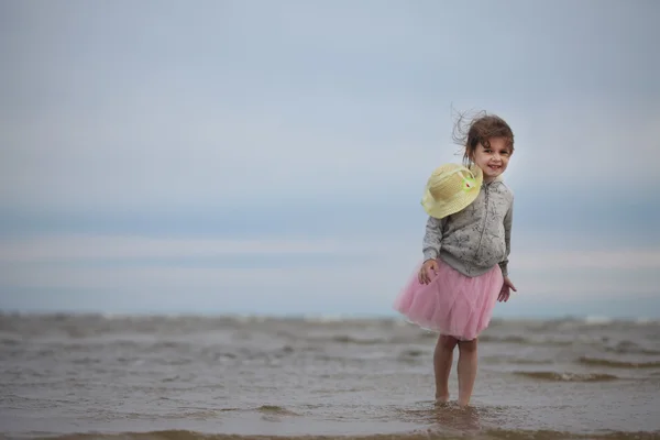 Niña de pie a orillas del mar arenoso — Foto de Stock