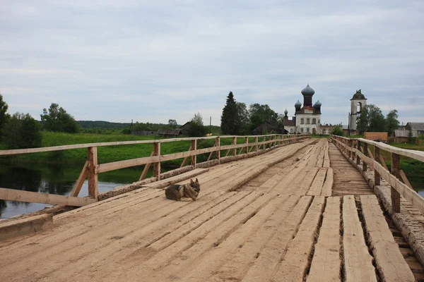 Old wooden bridge across the river. North Russia