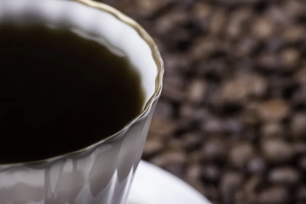 Tazza di caffè contro fagioli sfondo primo piano — Foto Stock