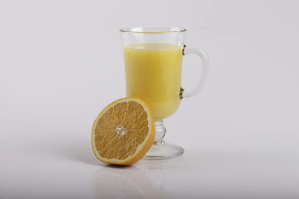 Стакан сока и нарезанный апельсин на белом — стоковое фото
