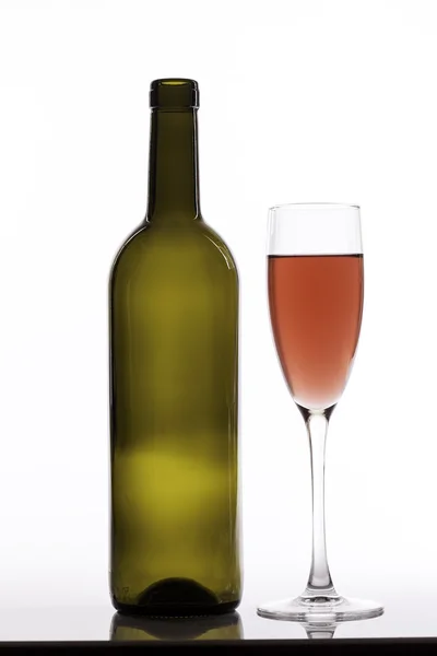Pohár rózsaszín bort és üres üveg fehér háttér — Stock Fotó