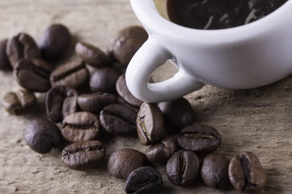 カップ、木の板のクローズ アップ上のコーヒー豆表示背景 — ストック写真
