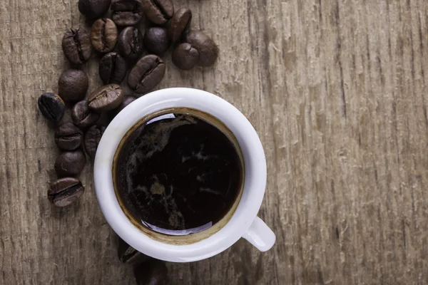 カップ、木の板のクローズ アップ上のコーヒー豆表示背景 — ストック写真