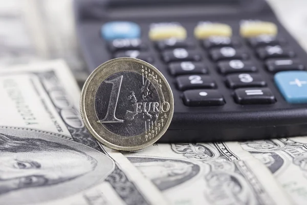 Moeda um euro close-up, calculadora sobre as notas de dólares — Fotografia de Stock