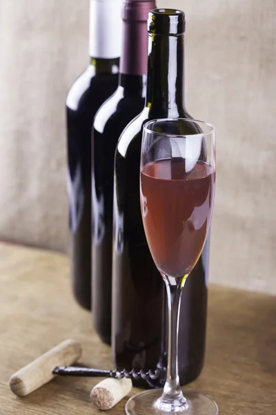 Glass of rose wine, corkscrew on the background bottles — Stock Photo, Image