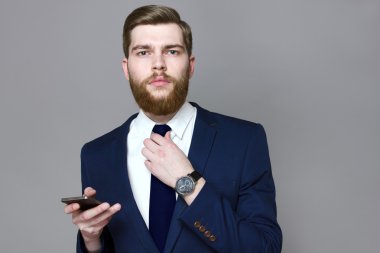 Acımak maiyet gri bir arka plan üzerinde giyen sakallı yakışıklı adam