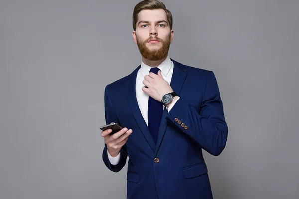 Barbudo hombre guapo usando suite inteligente sobre un fondo gris —  Fotos de Stock