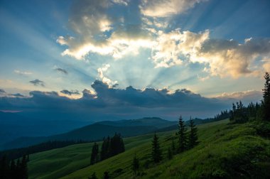 Akşam gökyüzündeki güneş ışınları bulutları delip geçiyor.