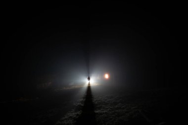 Dağlardaki sislerin içindeki ışık ışınlarının arka planındaki bir adamın silueti.