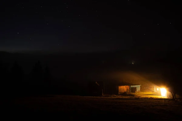 Rural house in fog at night in the carpathian mountains