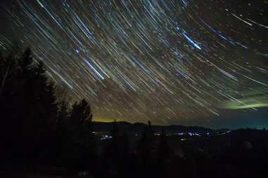 Gece gökyüzünde yıldız izleri Karpatlar ormanlarında.