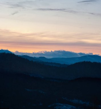 Günbatımının arka planında Karpat dağlarının ve ormanın siluetinin manzarası