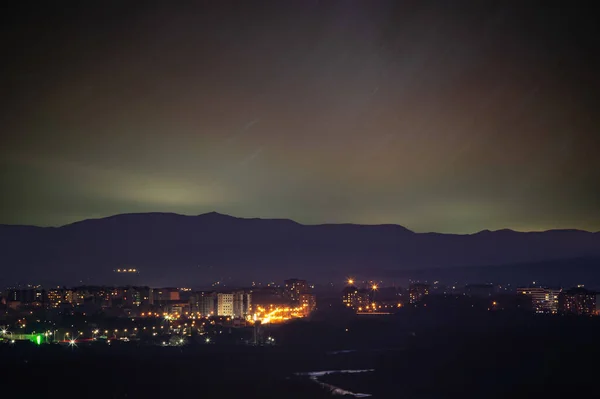 Gökyüzündeki Yıldız Izleri Arka Plandaki Dağlara Şehre Karşı — Stok fotoğraf