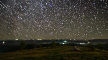 Baharda, dağlardaki yıldızların arka planında çadır.