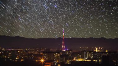 Gece şehrindeki TV kulesi yıldızların arka planına karşı