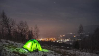 Karpat Dağları 'ndaki gece şehrinin arka planında bir zaman çadırı.
