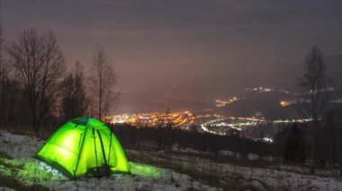 Karpat Dağları 'ndaki gece şehrinin arka planında bir zaman çadırı.