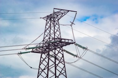 Gökyüzü ve bulutların arka planında yüksek voltaj güç hattı kulesi