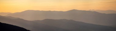 Gün batımında sisli Karpat dağlarının siluetleri. Güzel renkli bir manzara..