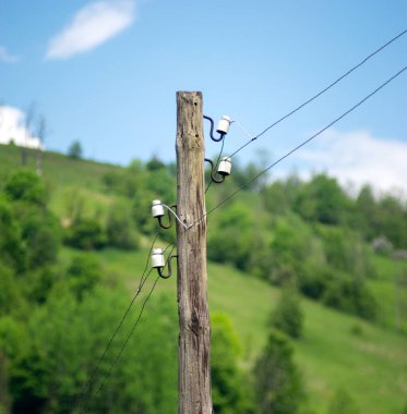 Dağlardaki mavi gökyüzünün arka planında eski ahşap elektrik direği