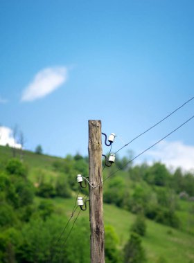 Dağlardaki mavi gökyüzünün arka planında eski ahşap elektrik direği