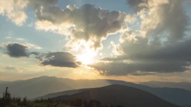 Günbatımında Ukrayna 'daki Karpat dağlarında güzel 4k hızlandırılmış güneş ışınları ve bulutlar.