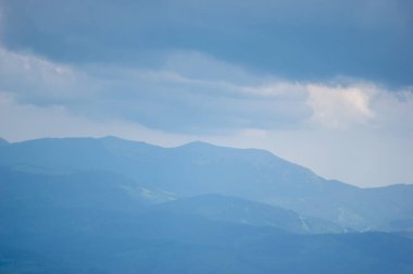 Baharda sisli havada mavi dağların manzarası. Ukrayna Karpatları