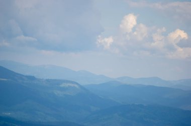 Baharda sisli havada mavi dağların manzarası. Ukrayna Karpatları