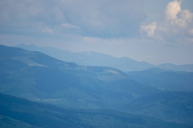 Baharda sisli havada mavi dağların manzarası. Ukrayna Karpatları