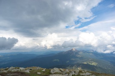 Karda ilkbahar dağları ve yeşil çimenler mavi gökyüzü ve beyaz bulutlara karşı