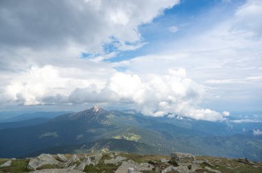 Karda ilkbahar dağları ve yeşil çimenler mavi gökyüzü ve beyaz bulutlara karşı