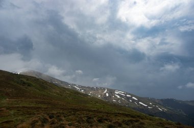 Yeşil bir ormanın arka planında karda bahar dağları. Ukrayna 'daki Karpatlar' ın güzel manzarası.