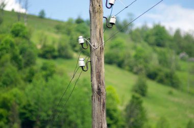 Dağlardaki mavi gökyüzünün arka planında eski ahşap elektrik direği