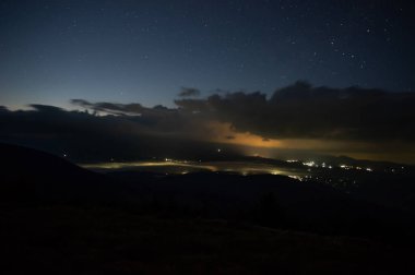 Bir dağ köyünde yağmur bulutları ve sis ile yıldızlı gökyüzü. Gece manzarası.