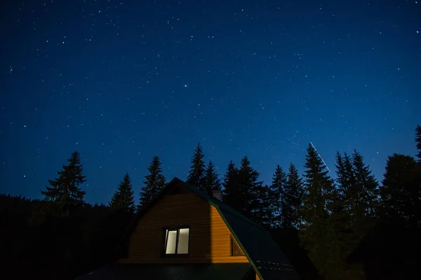 美丽的夜景 森林中的房子映衬着喀尔巴阡山脉星空的映衬 图库图片